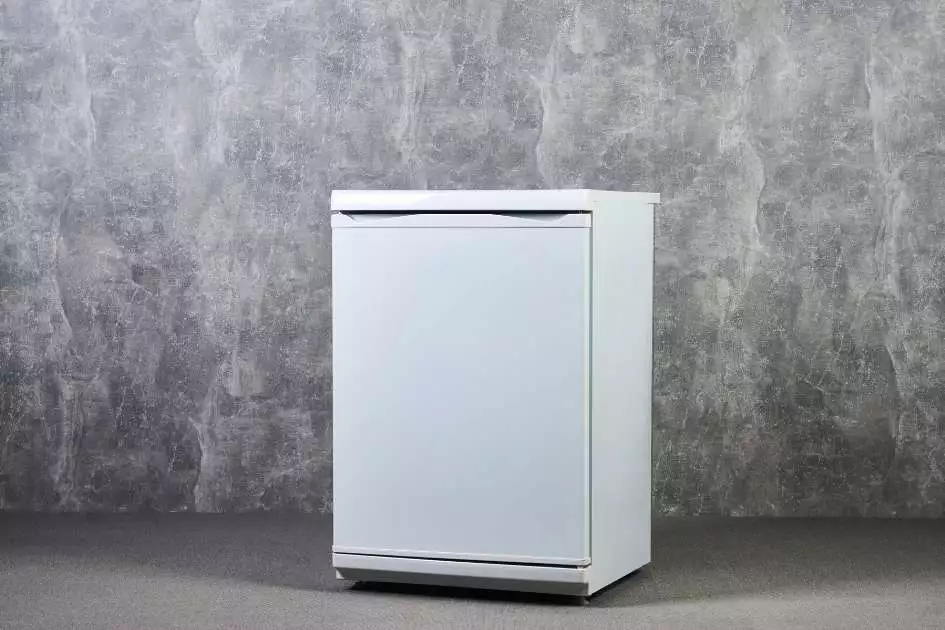 white single door fridge in front of a gray wall in the kitchen