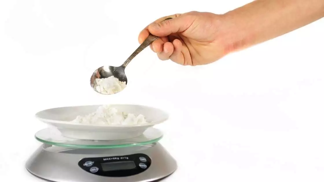 Measuring hand poured flour on a kitchen scale