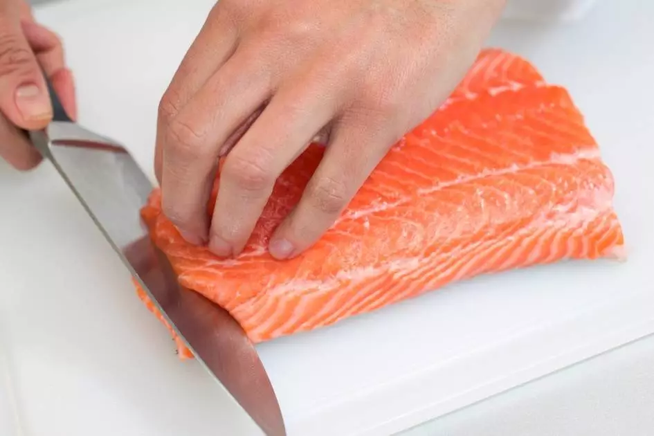 chef slicing sushi on a white cutting board